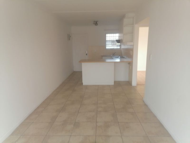An open-plan living and kitchen area featuring tiled flooring, a breakfast bar, and built-in kitchen cabinetry.