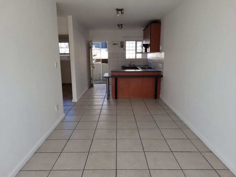 An open-plan living and kitchen area featuring tiled flooring, built-in cabinetry, a breakfast bar, and direct access to an outdoor space.