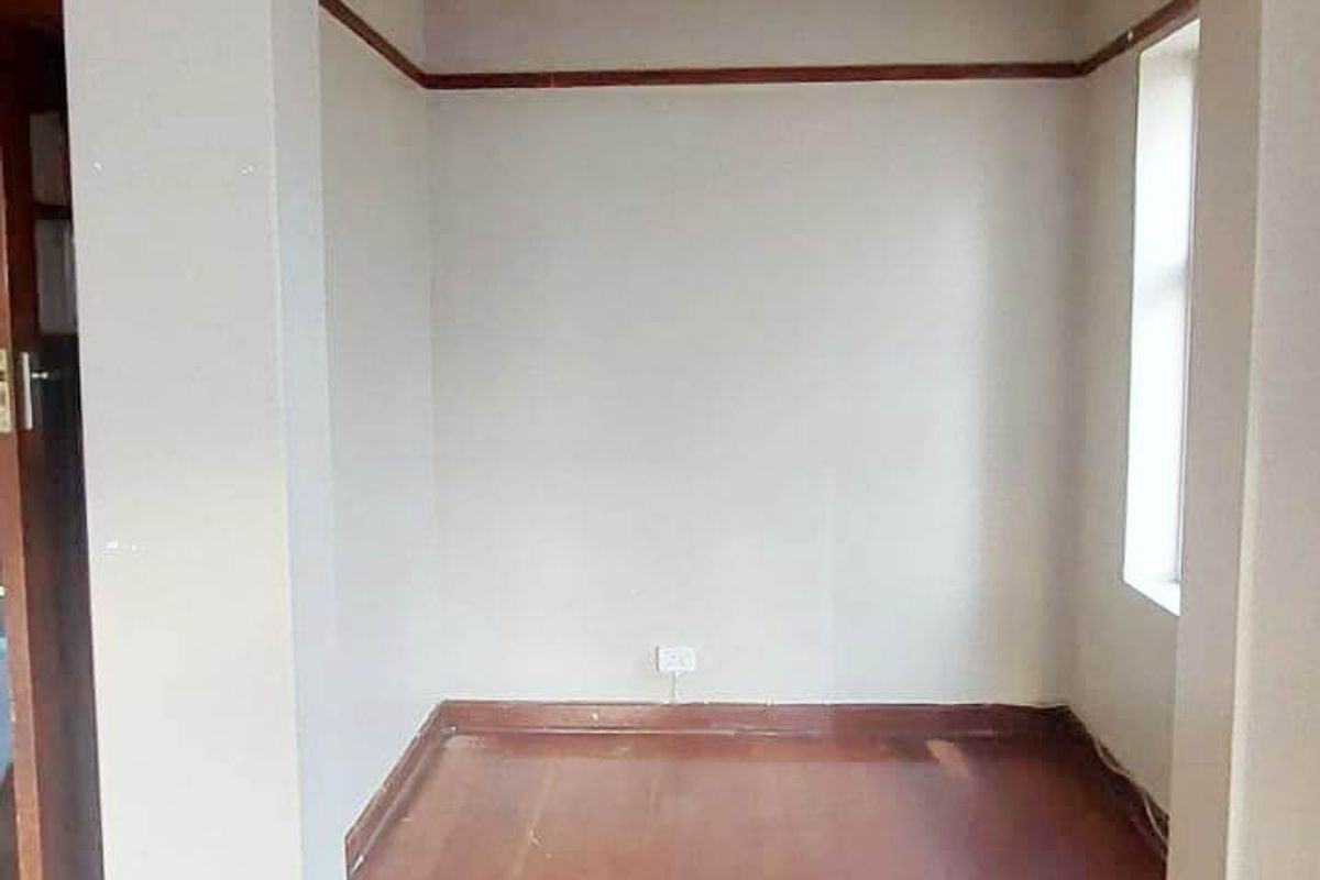 An empty living area featuring original timber flooring, timber picture rails, and skirting boards, presenting a blank canvas for renovation.
