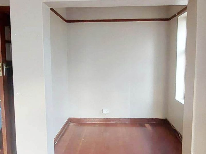 An empty living area featuring original timber flooring, timber picture rails, and skirting boards, presenting a blank canvas for renovation.