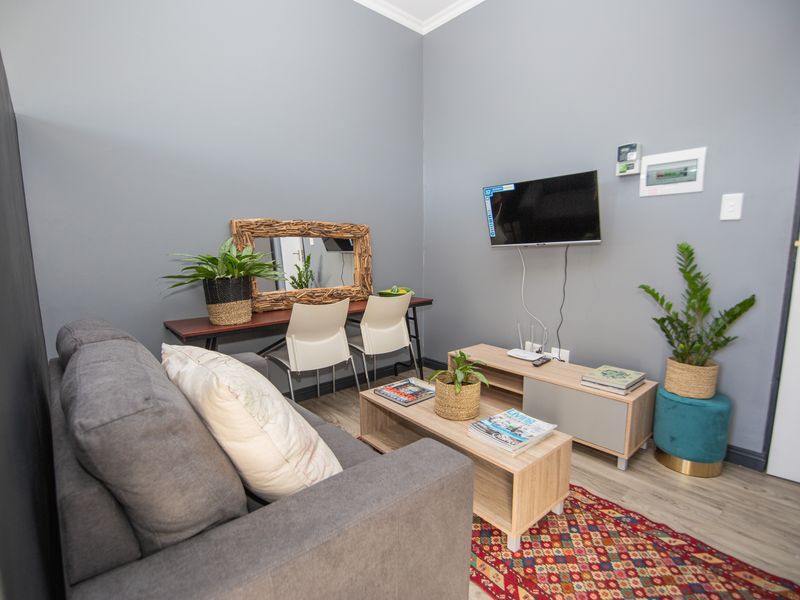 A well-maintained living room featuring grey walls, light wood-look laminate flooring, and modern skirting boards.