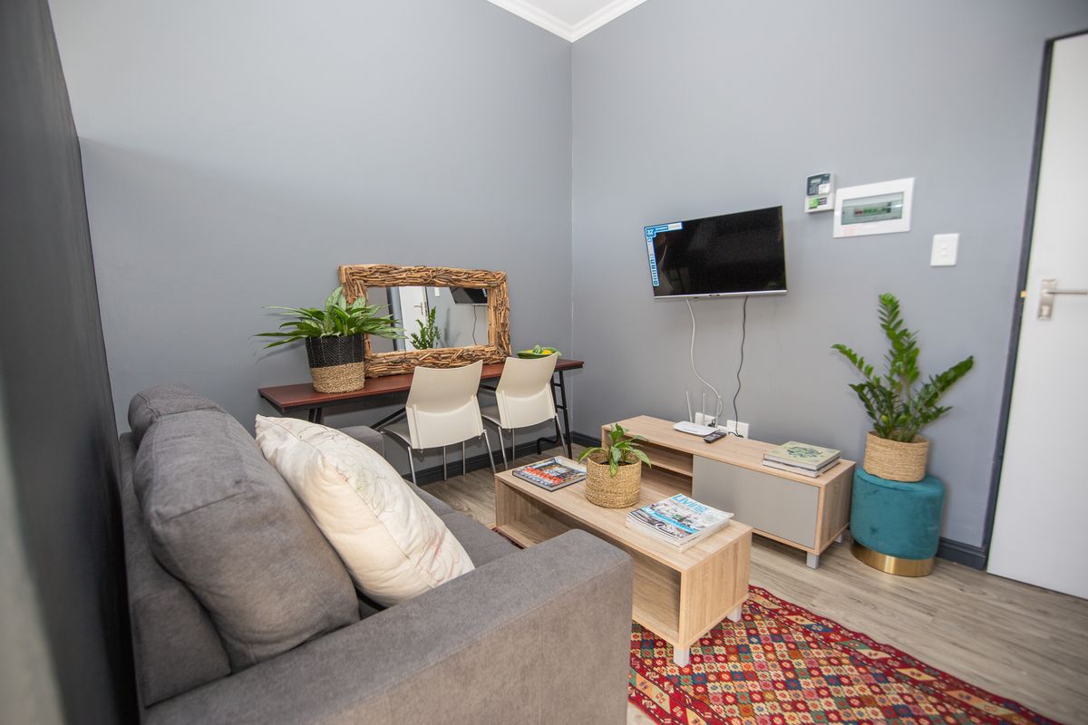 A well-maintained living room featuring grey walls, light wood-look laminate flooring, and modern skirting boards.