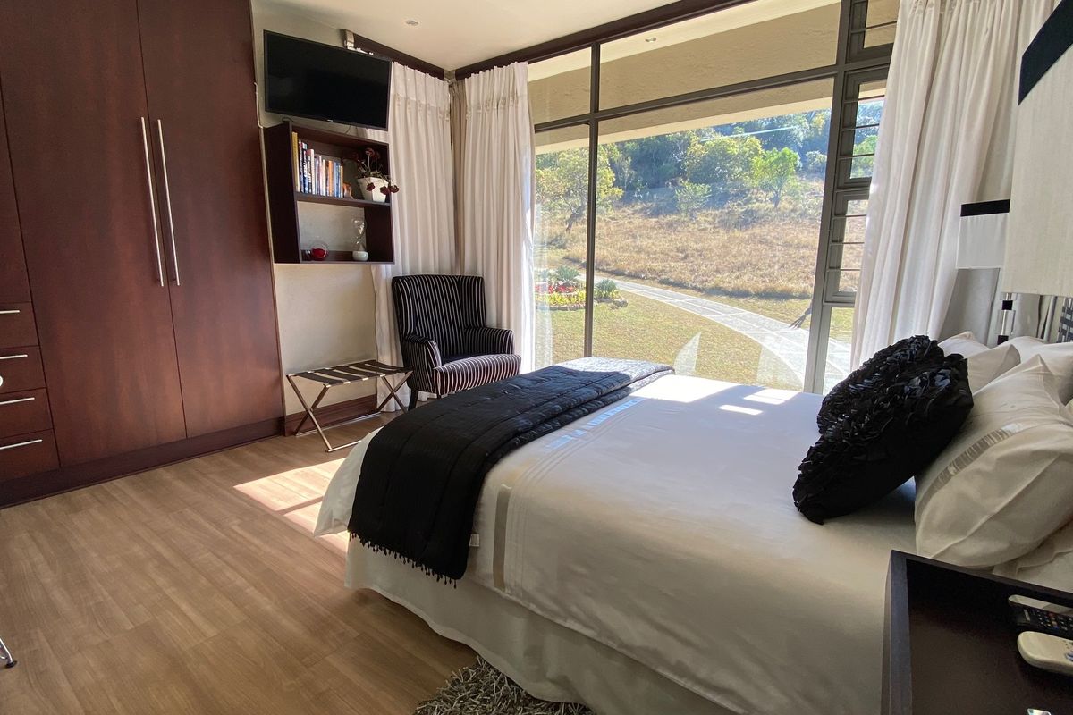 A well-lit bedroom featuring floor-to-ceiling windows with scenic views, built-in wooden cabinetry, and modern laminate flooring.
