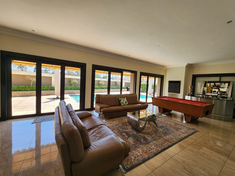 Spacious living area featuring large sliding glass doors opening to the pool area, tiled flooring, recessed lighting, and a built-in bar.