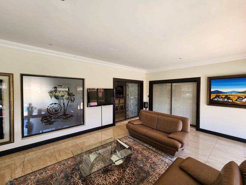 Spacious living room featuring polished tile flooring, crown molding, recessed lighting, and sliding glass doors providing access to adjacent areas.
