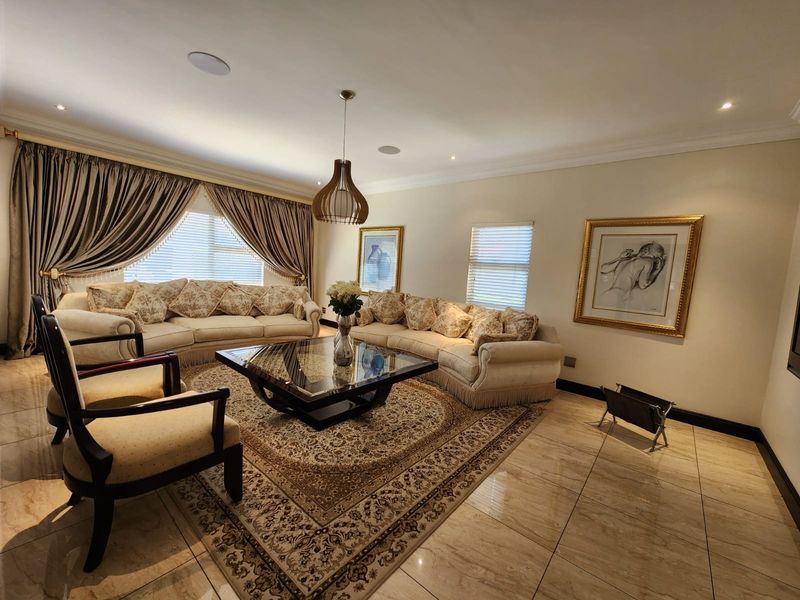 Spacious living room featuring polished tile flooring, recessed ceiling lighting, integrated ceiling speakers, and decorative cove cornicing.