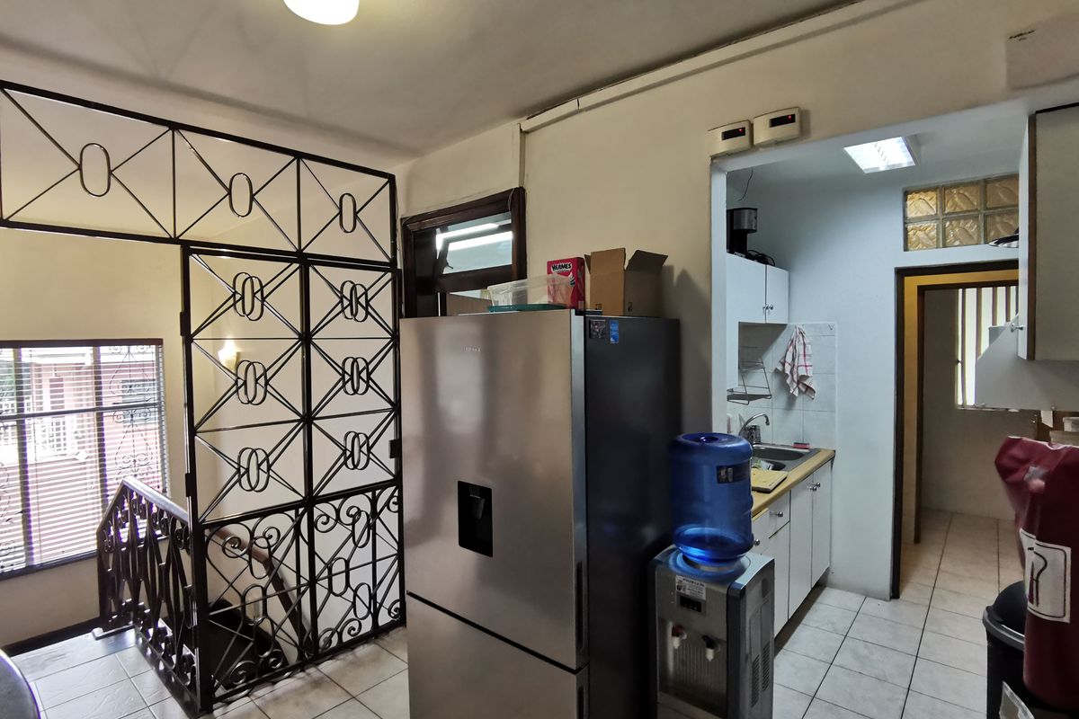 A functional kitchen area featuring tiled flooring, built-in cabinetry, and a decorative metal security screen partition leading to the staircase.