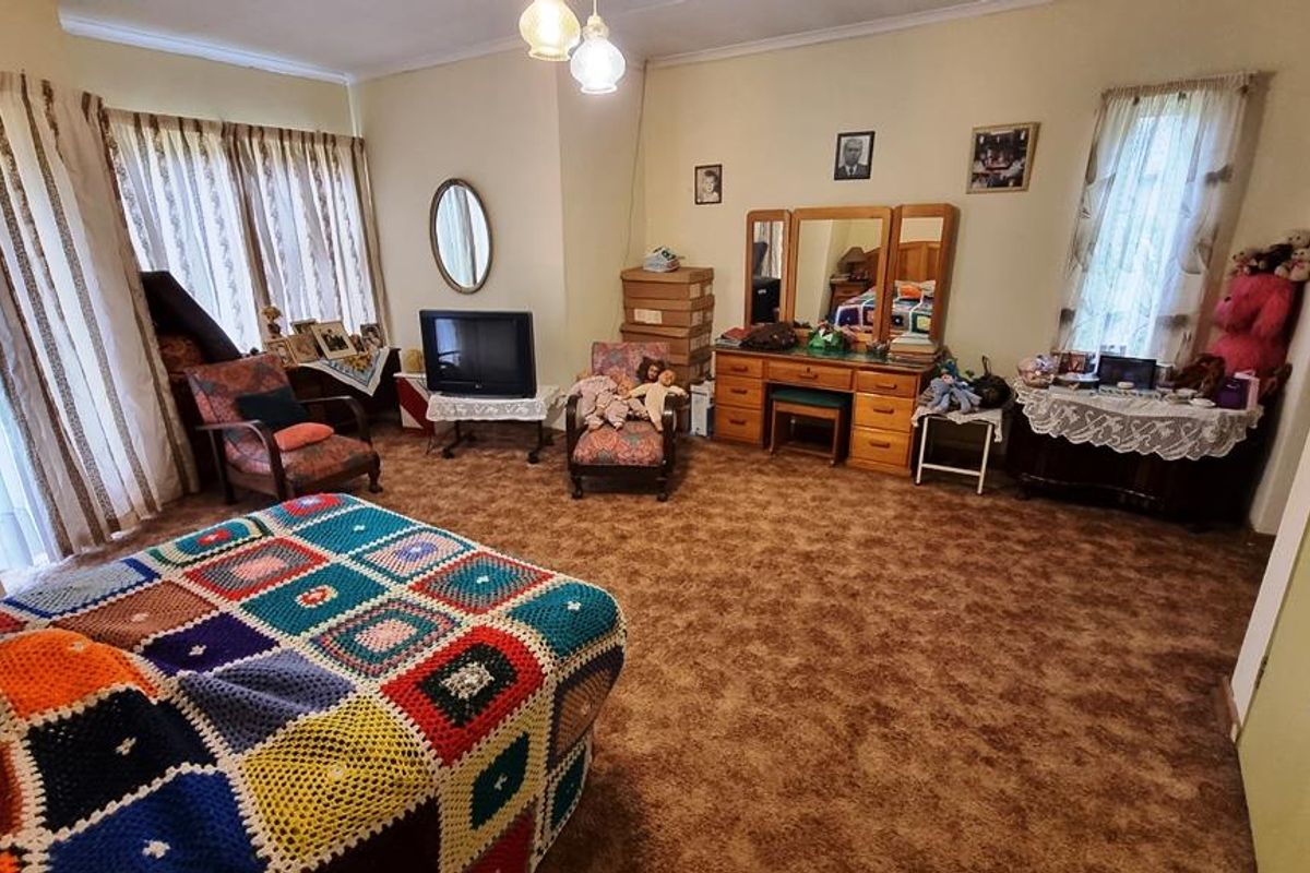 Spacious bedroom featuring large windows with curtains, carpeted flooring, and ample room for bedroom furniture.