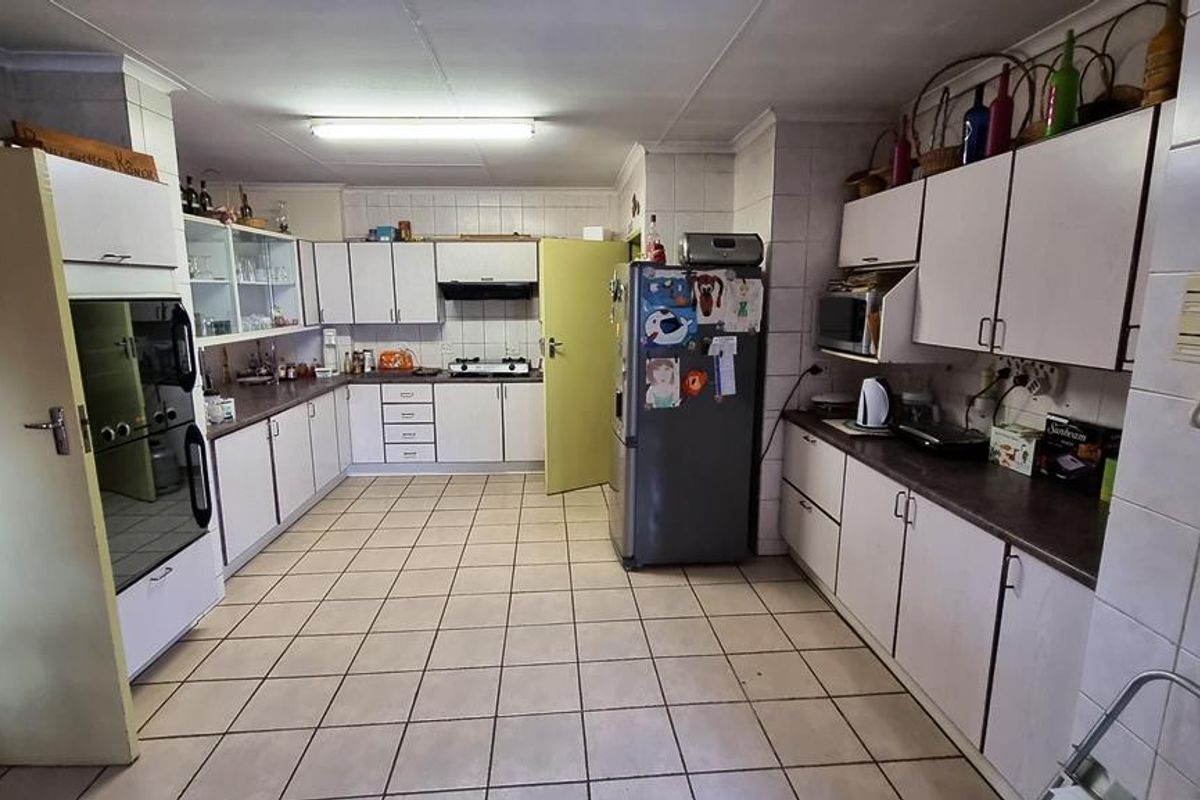Spacious kitchen featuring extensive cabinetry, tiled flooring, built-in oven, and hob, offering a functional layout with ample storage and workspace.