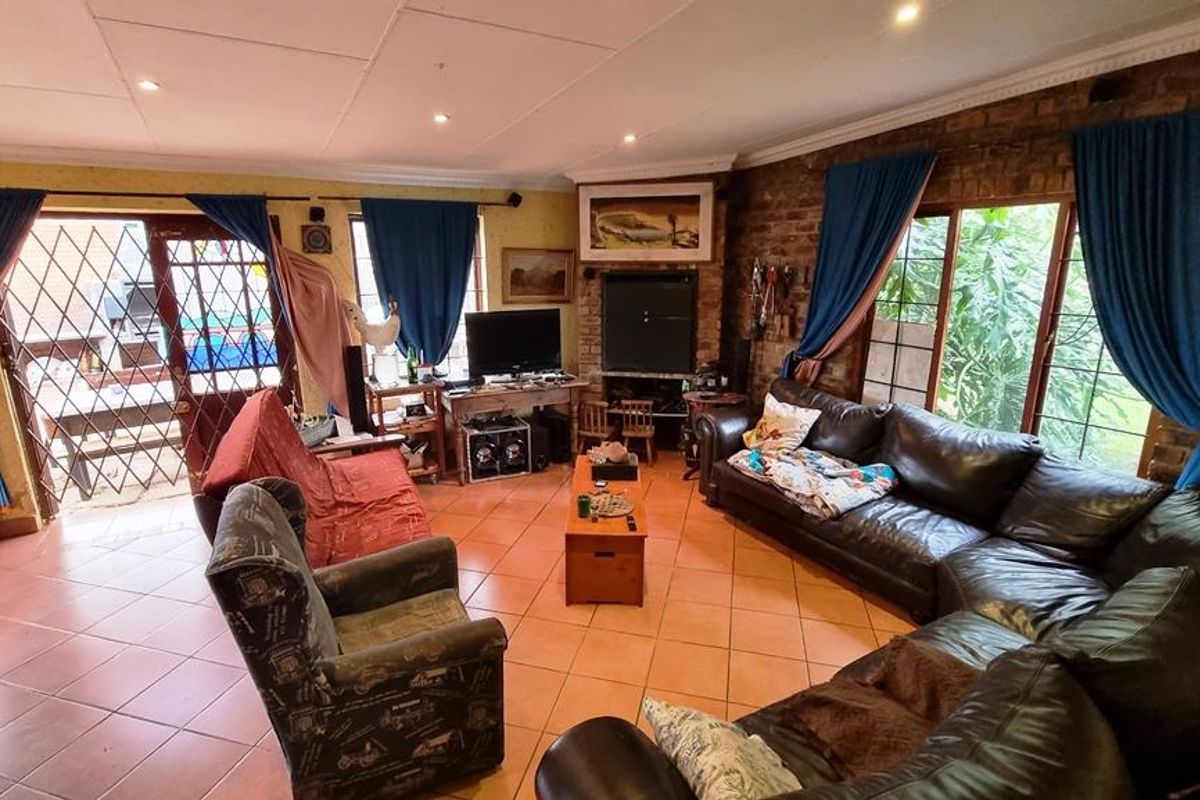 Spacious living room featuring exposed brick feature walls, tiled flooring, and large windows providing natural light and access to the outdoor patio area.