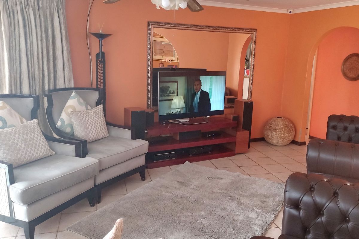 A living room featuring tiled flooring, arched wall openings, and a large wall-mounted mirror.