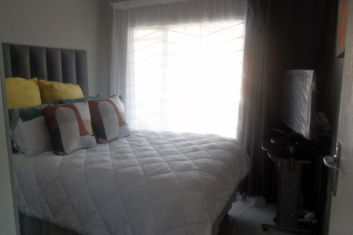 A bedroom featuring a window with security bars and neutral wall finishes.