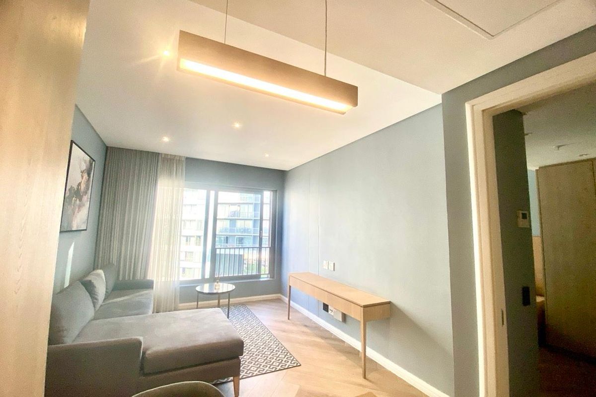 Modern living room featuring herringbone timber flooring, neutral blue-toned walls, and a sleek built-in console unit with integrated lighting.