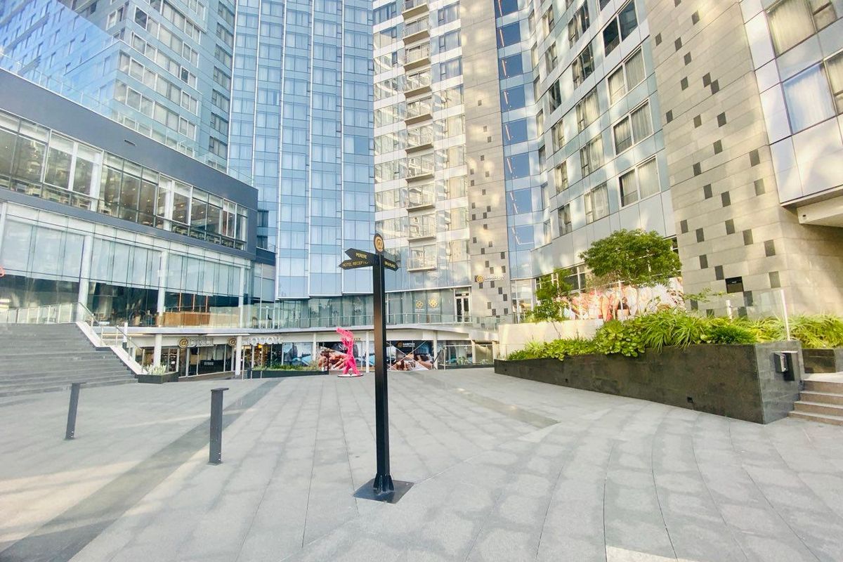 A modern paved courtyard area situated between high-rise apartment towers, featuring landscaped planters and contemporary architectural design.