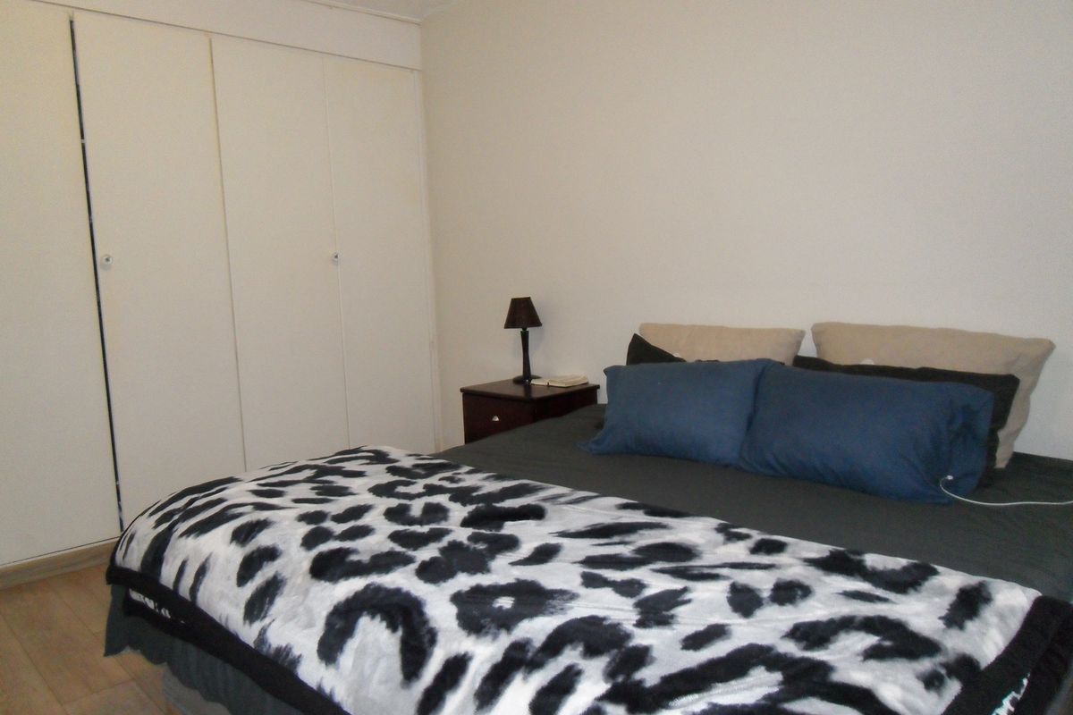 A bedroom featuring built-in cupboards and laminate flooring.