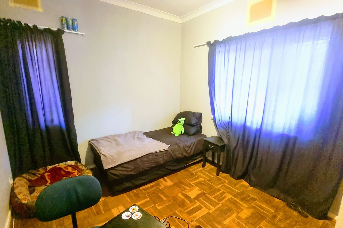 A bedroom featuring parquet flooring, coved ceilings, and dual windows with curtain fixtures.