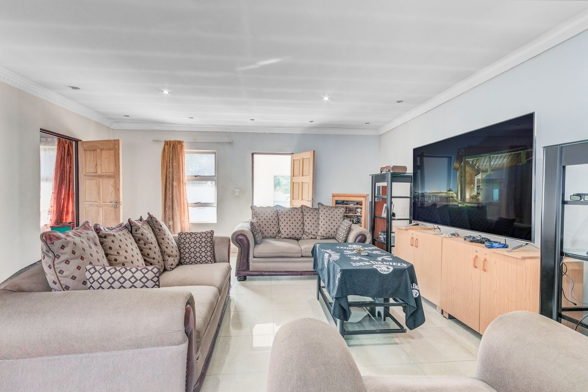 Spacious living room featuring tiled flooring, recessed ceiling lighting, and direct access to the exterior through a wooden door.