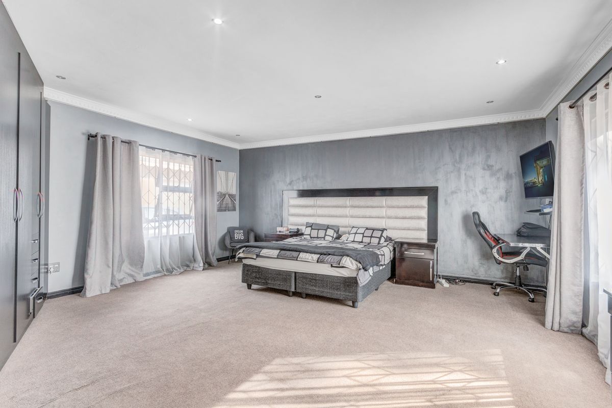 Spacious bedroom featuring a built-in wardrobe, recessed ceiling lighting, and a feature wall with a neutral carpet finish.