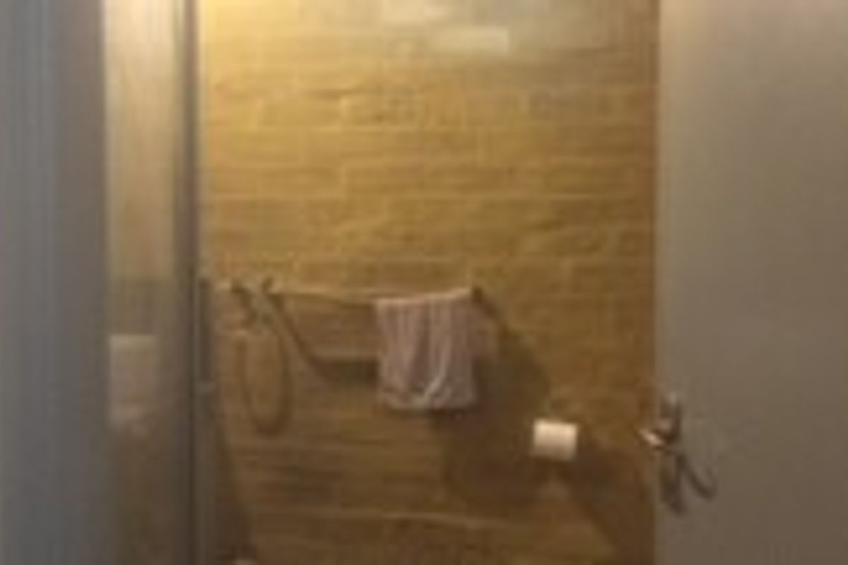 A functional bathroom featuring a shower enclosure with tiled walls and integrated fixtures.