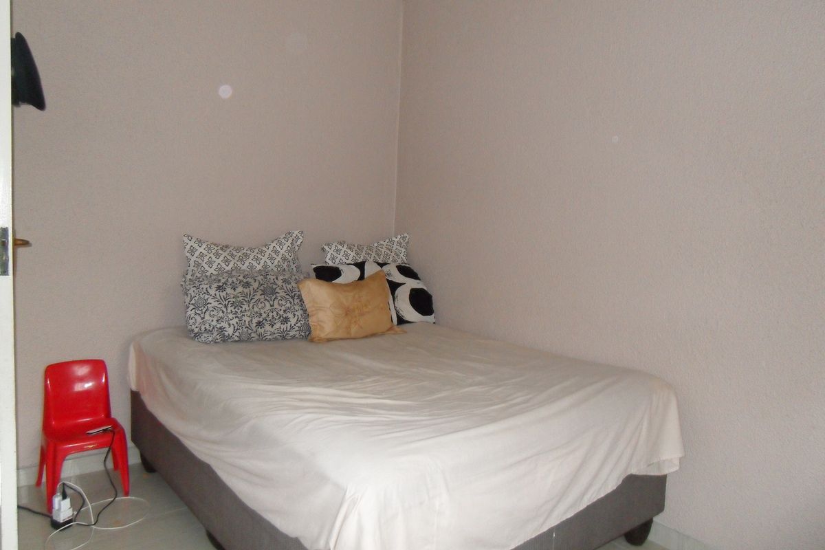 A simple bedroom featuring neutral wall tones and tiled flooring, providing a functional and straightforward living space.