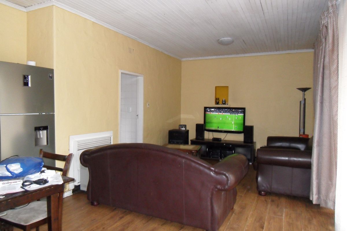 A living room featuring wood-look flooring, yellow painted walls, and a white tongue-and-groove ceiling, providing a functional and lived-in living space.