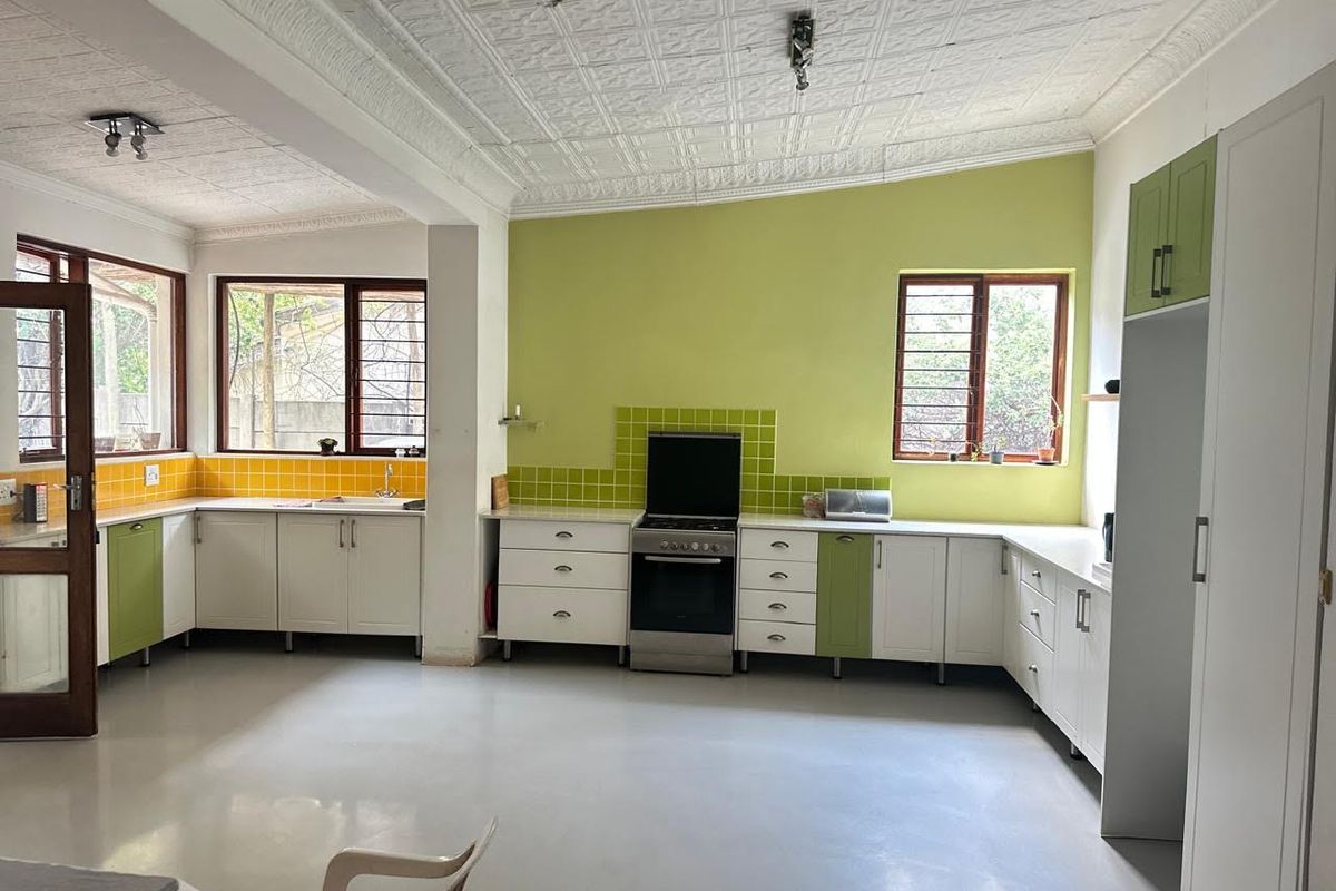 Spacious kitchen featuring ample cabinetry, a freestanding stove, tiled splashbacks, and large windows providing natural light throughout the workspace.