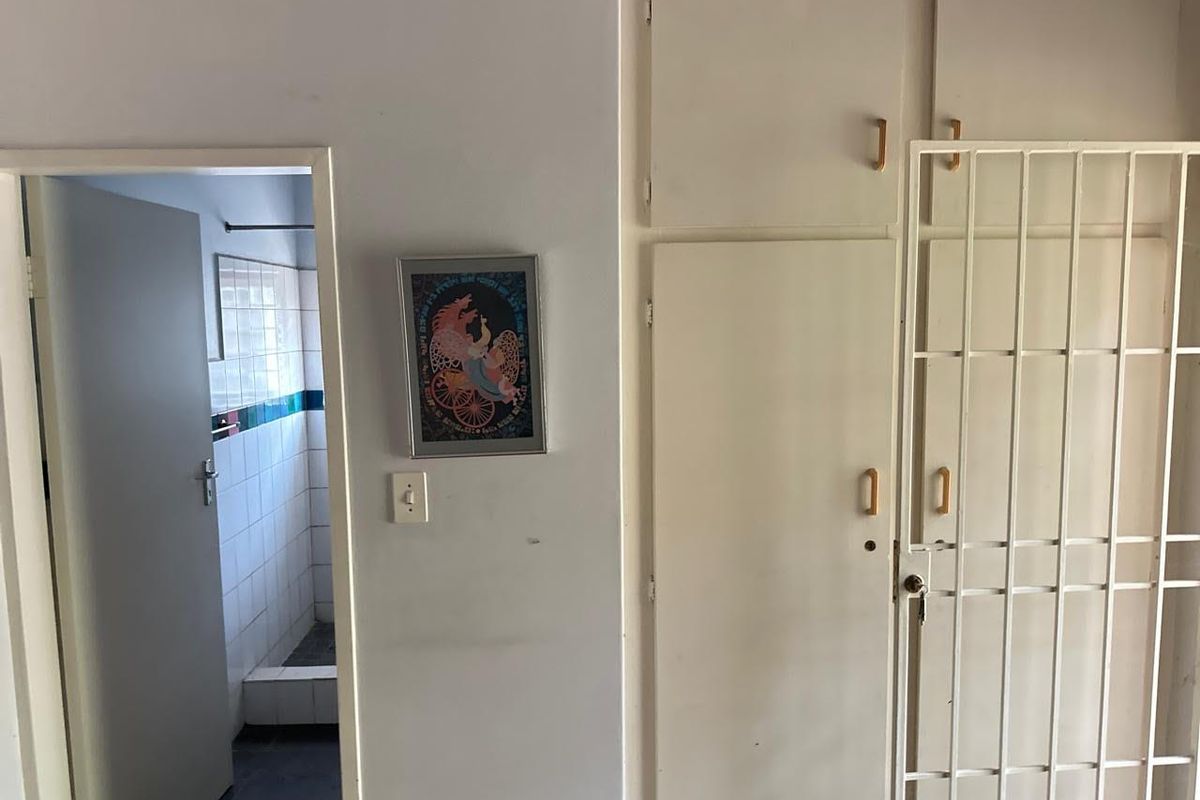 A bedroom interior featuring built-in storage cupboards and a doorway leading to an adjacent tiled bathroom area.