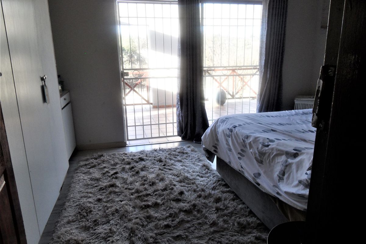 Bedroom featuring built-in cupboards and sliding glass doors with security gate, providing direct access to an outdoor patio area.