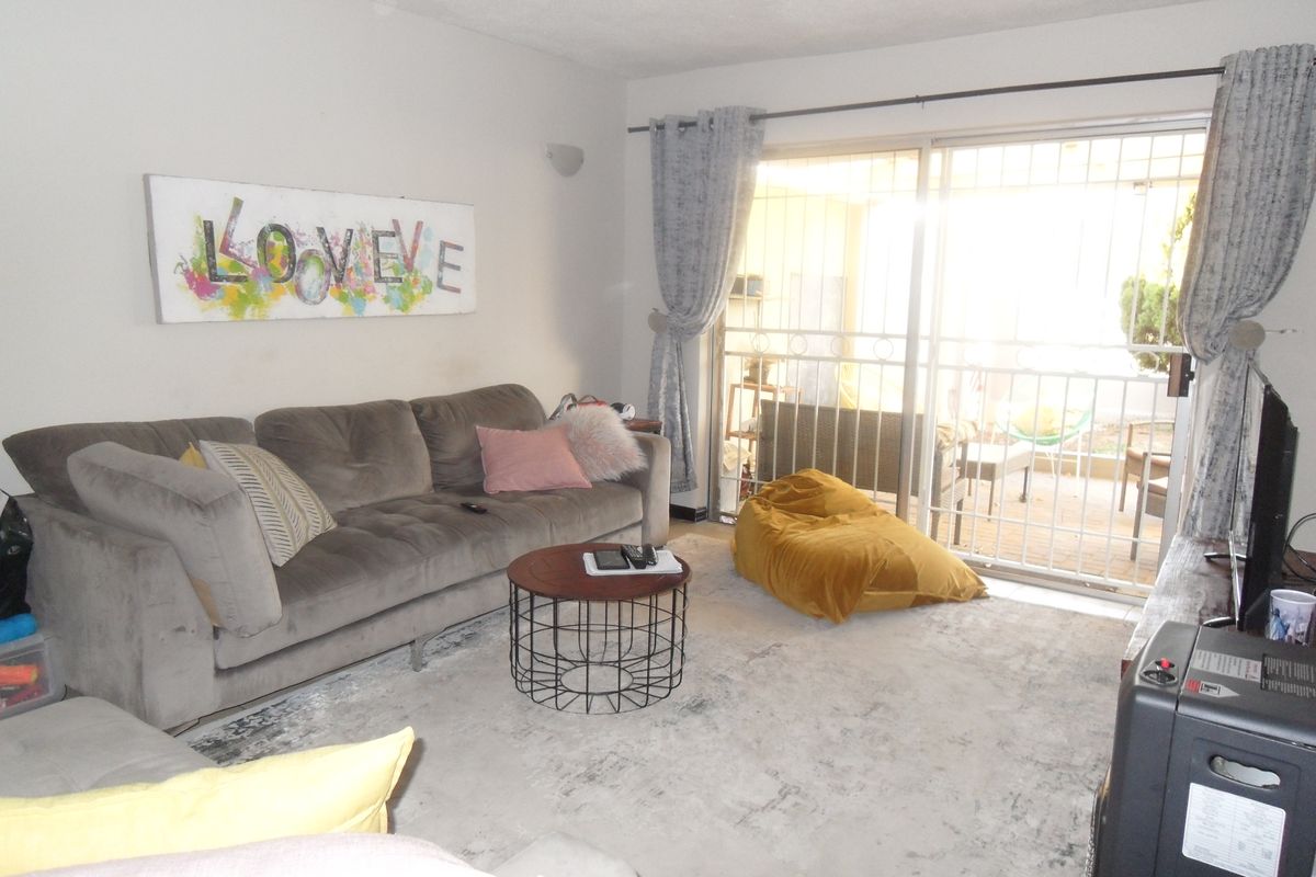 A living room featuring large sliding glass doors with security bars, providing access to an outdoor patio area.