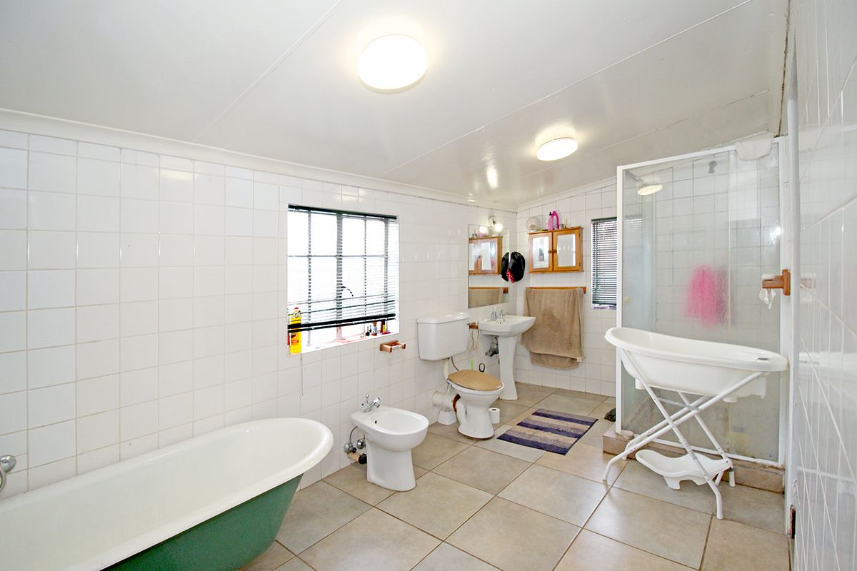 Spacious bathroom featuring a freestanding bathtub, separate glass-enclosed shower, pedestal basin, toilet, and bidet with tiled walls and flooring.