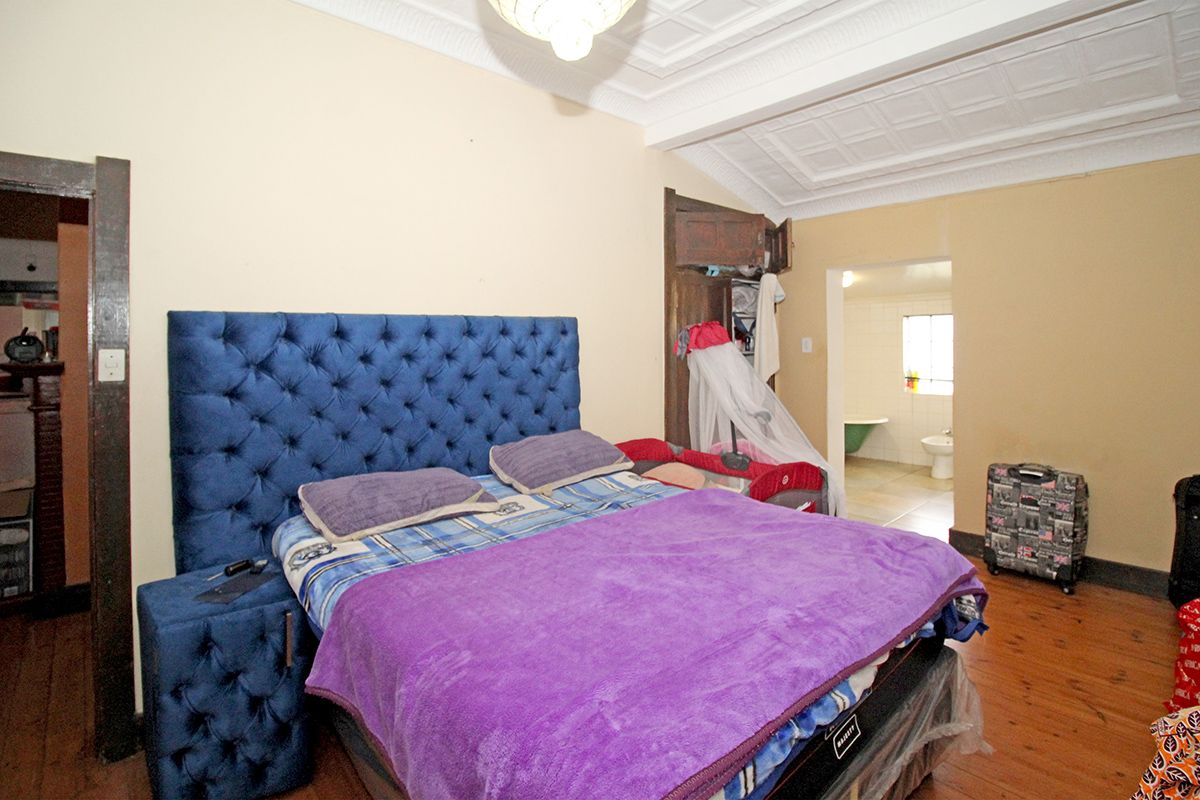 A bedroom featuring original pressed metal ceilings, timber flooring, and an en-suite bathroom access.