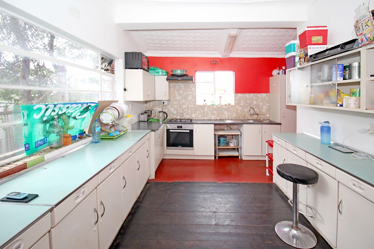 A dated kitchen featuring built-in cabinetry, a gas hob, an integrated oven, and a large window providing natural light.