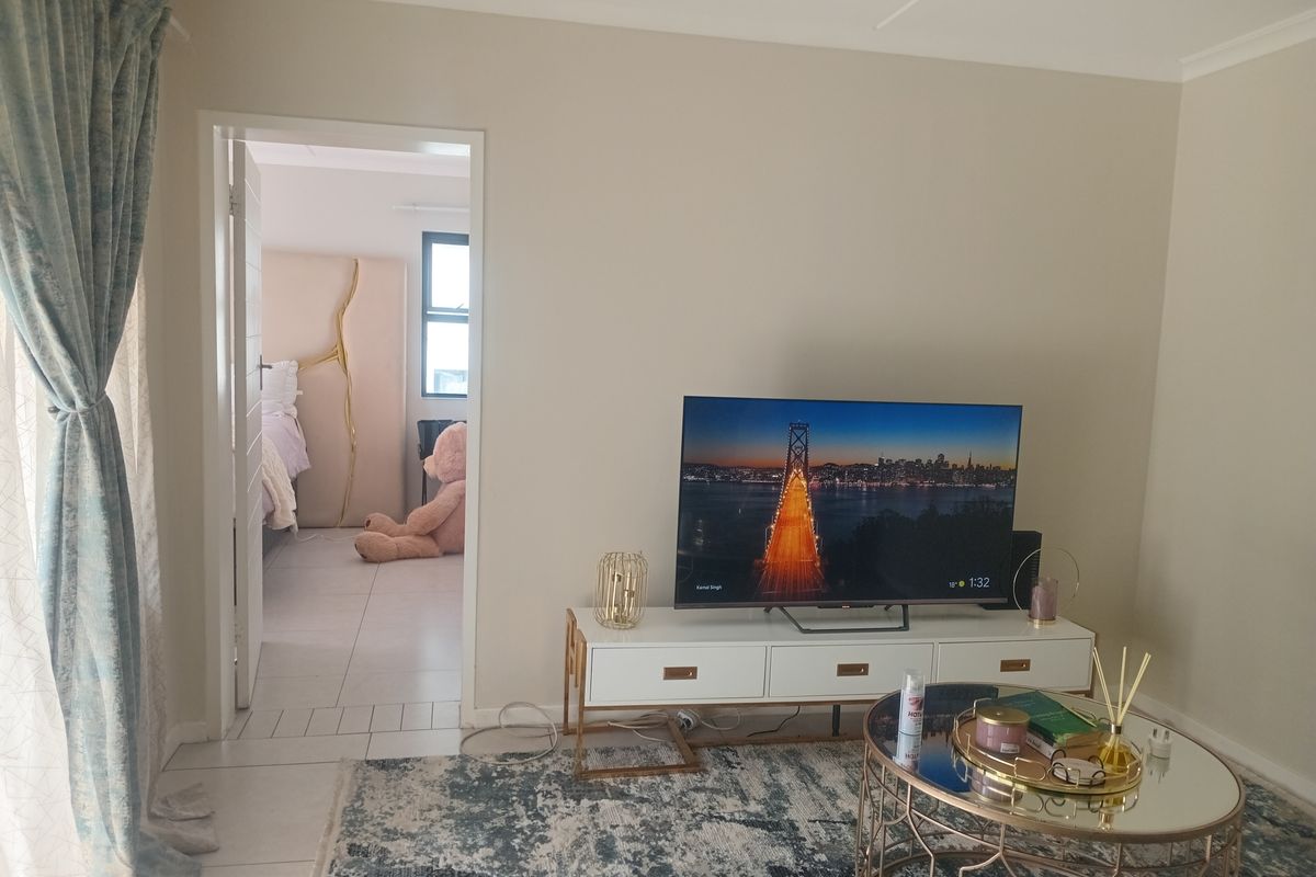 A bright living room featuring tiled flooring and a doorway leading to an adjacent bedroom.