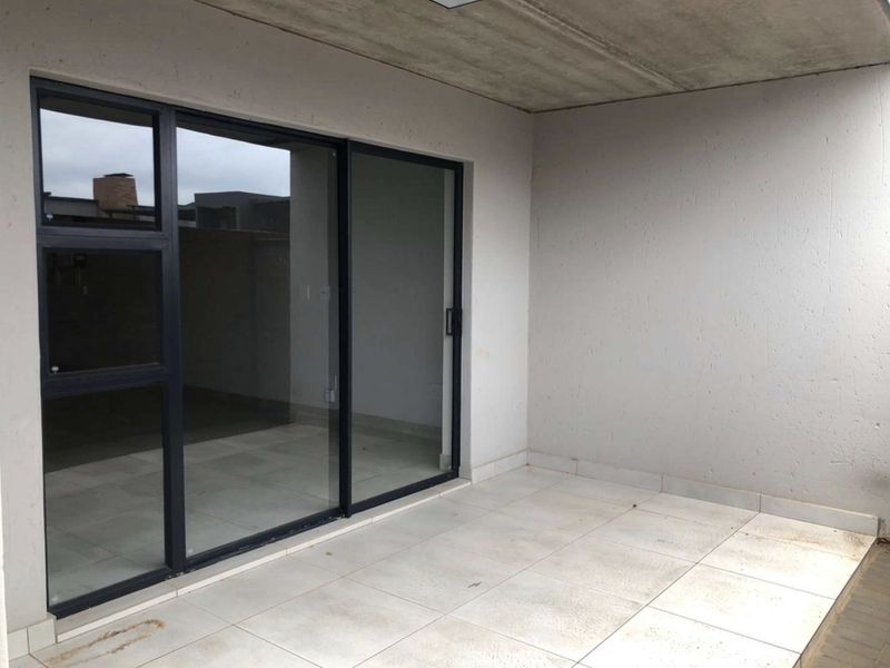 A covered patio area featuring tiled flooring and a large sliding glass door providing access to the interior living space.