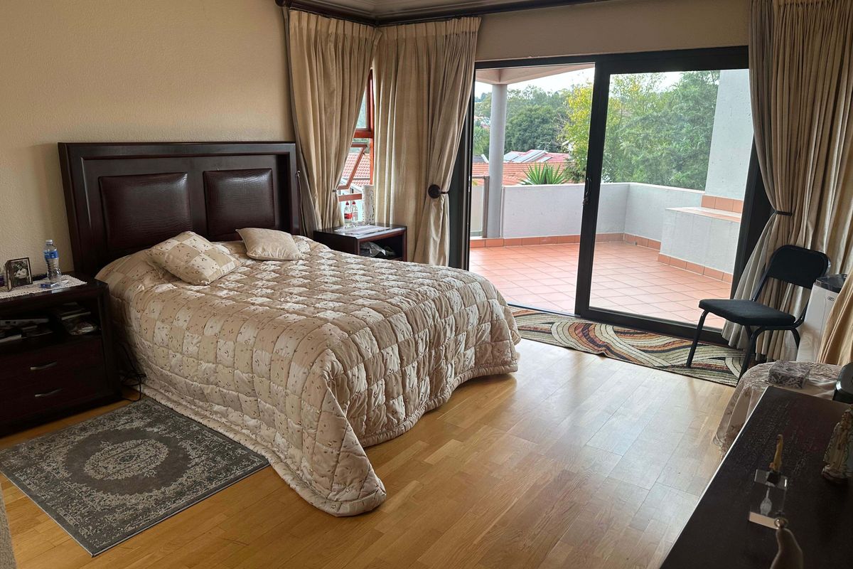 Spacious bedroom featuring laminate flooring, large sliding glass doors, and direct access to a private covered balcony with outdoor views.