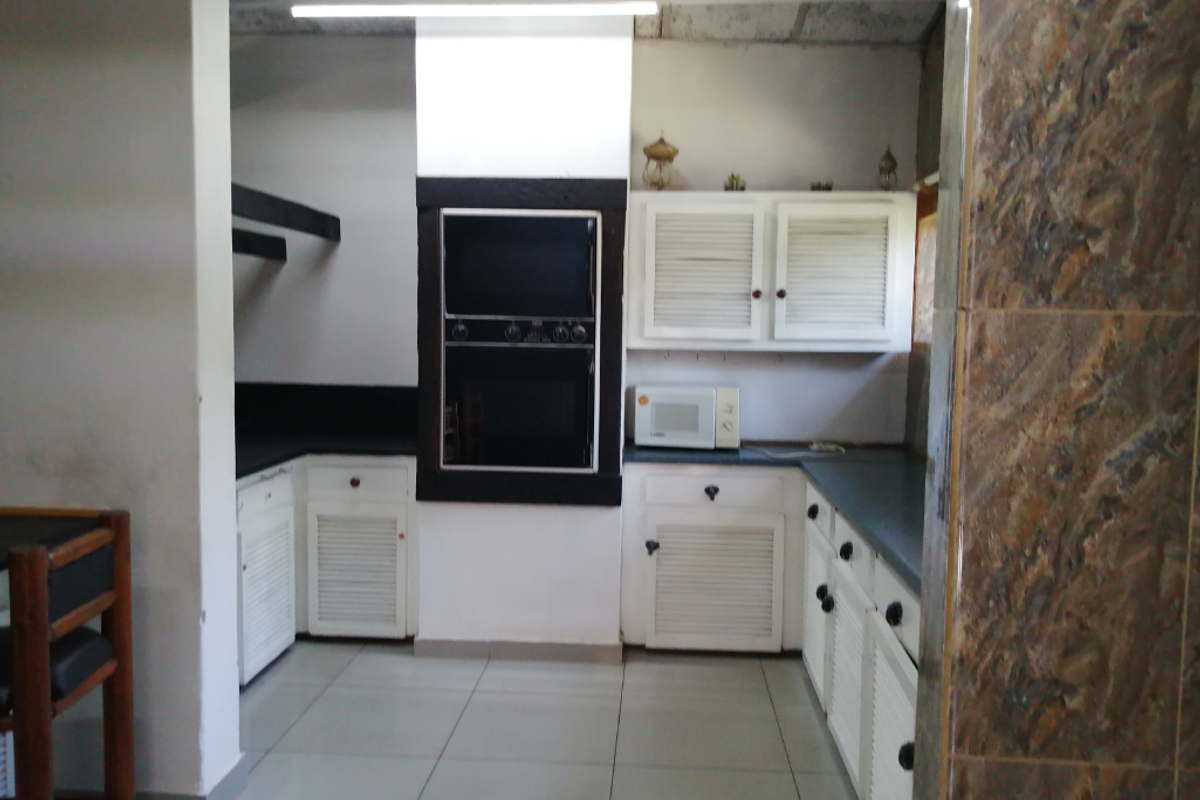 A functional kitchen featuring white louvered cabinetry, built-in double oven, dark countertops, and tiled flooring.