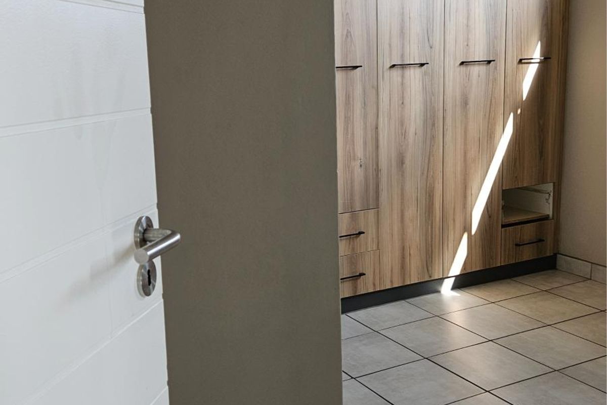 A bedroom featuring built-in wooden cabinetry with integrated storage and neutral floor tiling.
