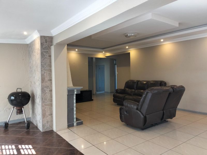 Spacious open-plan living area featuring tiled flooring, a built-in fireplace, and decorative ceiling details with recessed lighting.