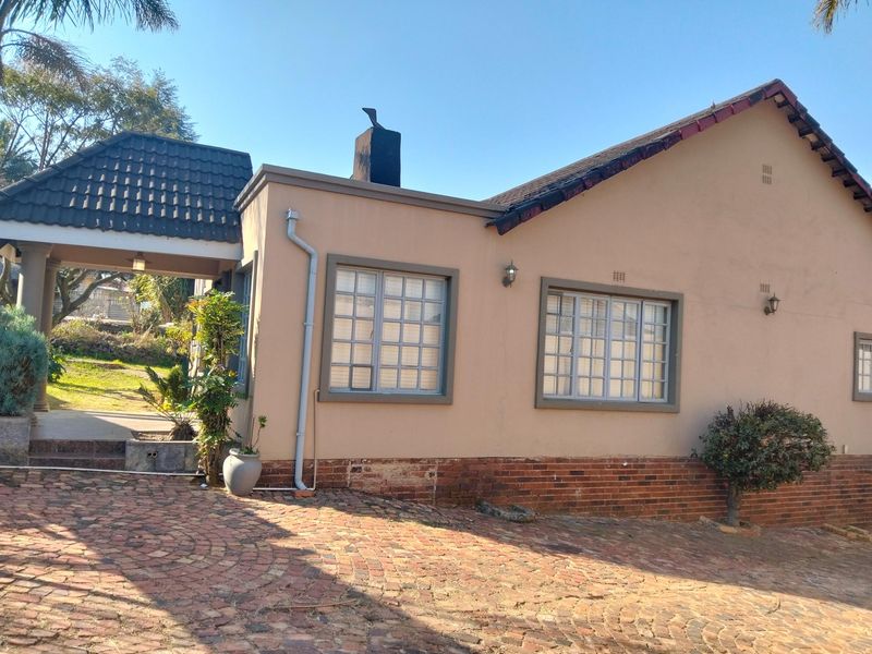 Front elevation of a house featuring a brick driveway, covered entrance, and a combination of plastered and brick facade finishes.