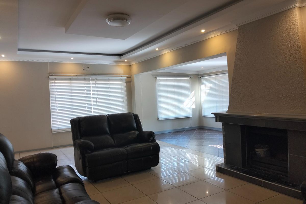 Spacious living room featuring a built-in fireplace, recessed ceiling with downlights, and neutral tiled flooring throughout.