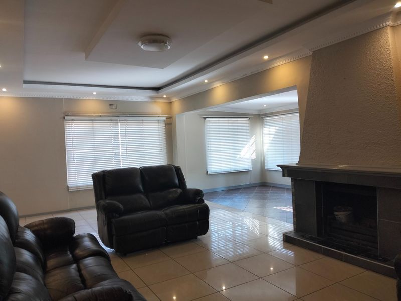 Spacious living room featuring a built-in fireplace, recessed ceiling with downlights, and neutral tiled flooring throughout.