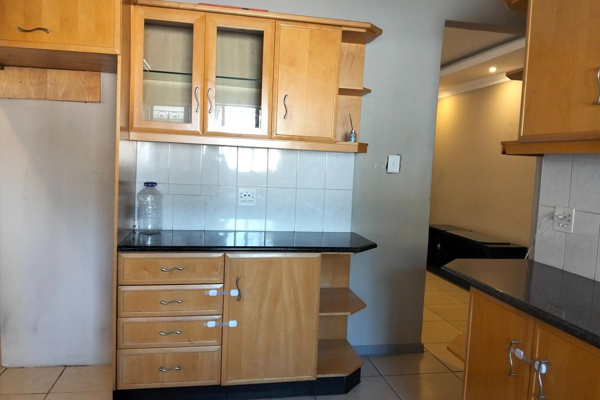 A functional kitchen area featuring wooden cabinetry, granite countertops, and tiled backsplash, offering a clean and practical layout for culinary activities.