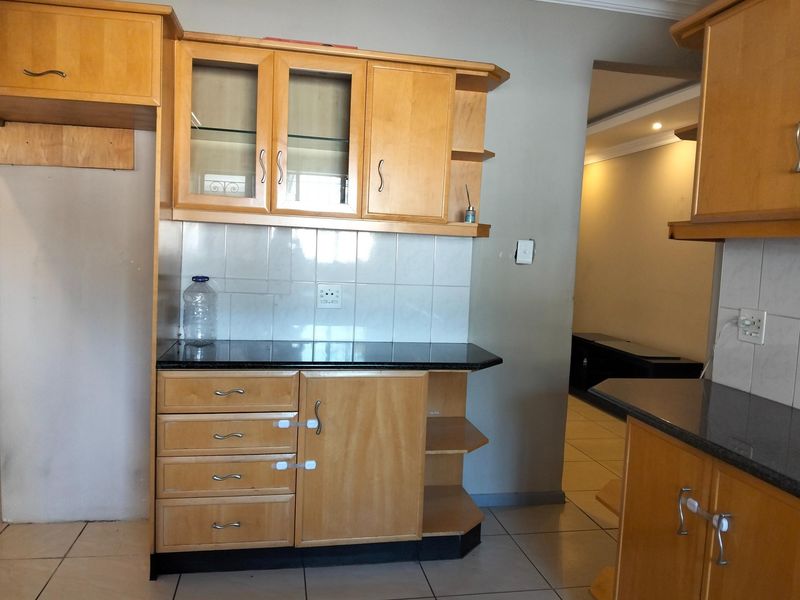 A functional kitchen area featuring wooden cabinetry, granite countertops, and tiled backsplash, offering a clean and practical layout for culinary activities.