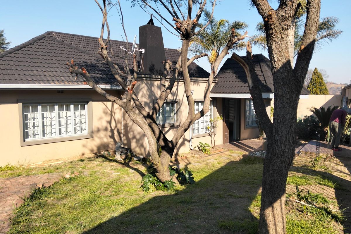 Rear view of the house featuring a tiled roof, chimney, and paved walkway leading to the entrance.