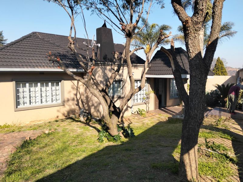 Rear view of the house featuring a tiled roof, chimney, and paved walkway leading to the entrance.
