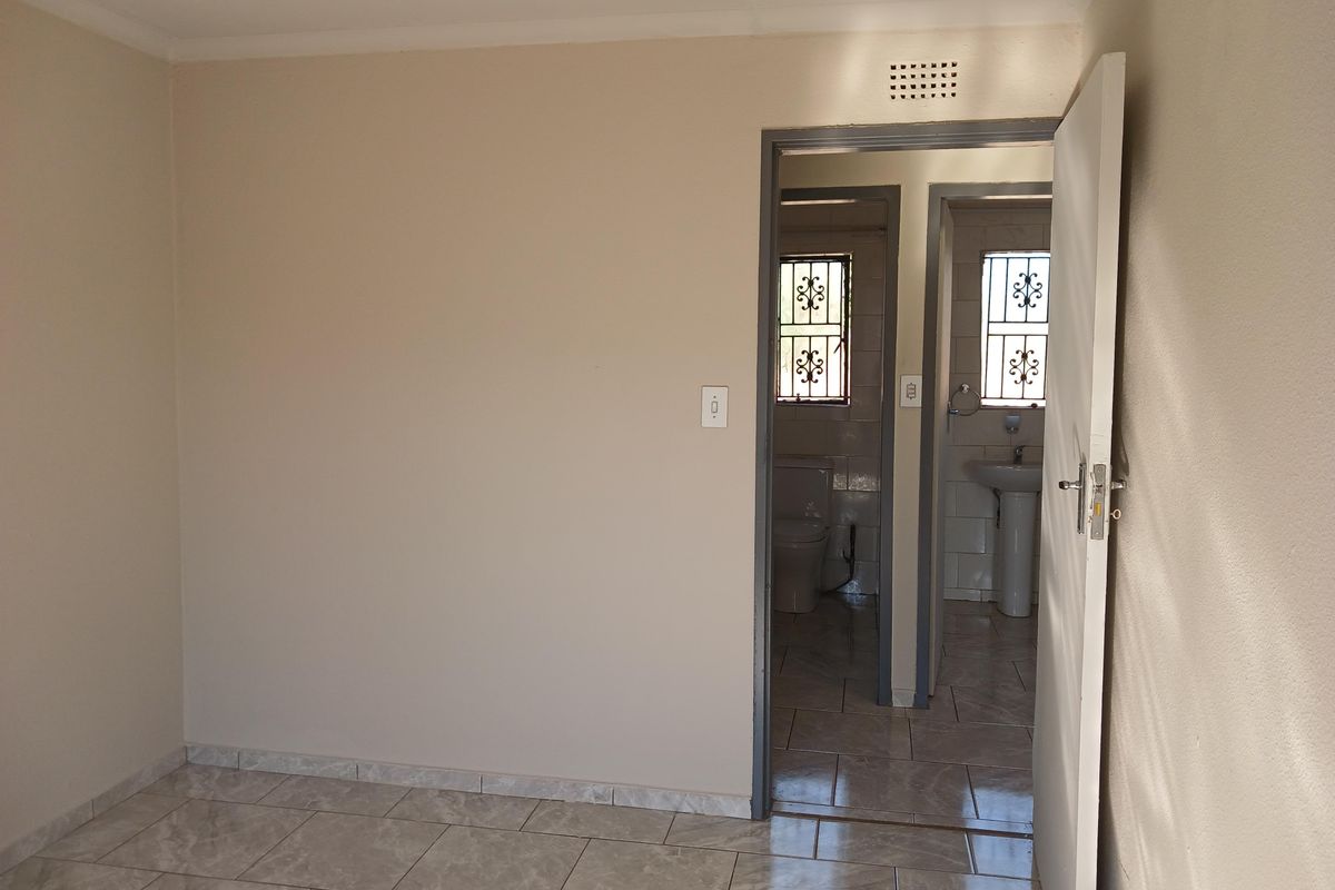 A view from a bedroom looking into an adjacent bathroom featuring tiled flooring and standard sanitary fixtures.