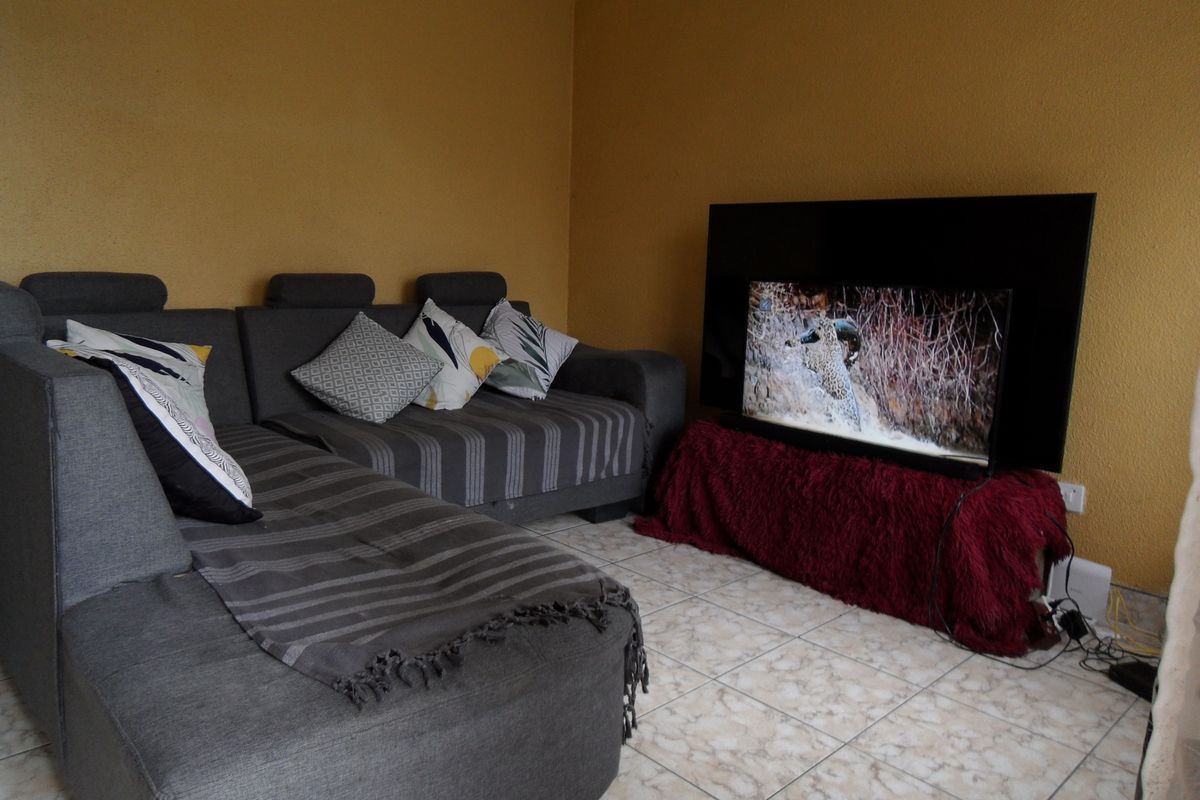 A living room area featuring tiled flooring and textured wall finishes, providing a functional space for relaxation.