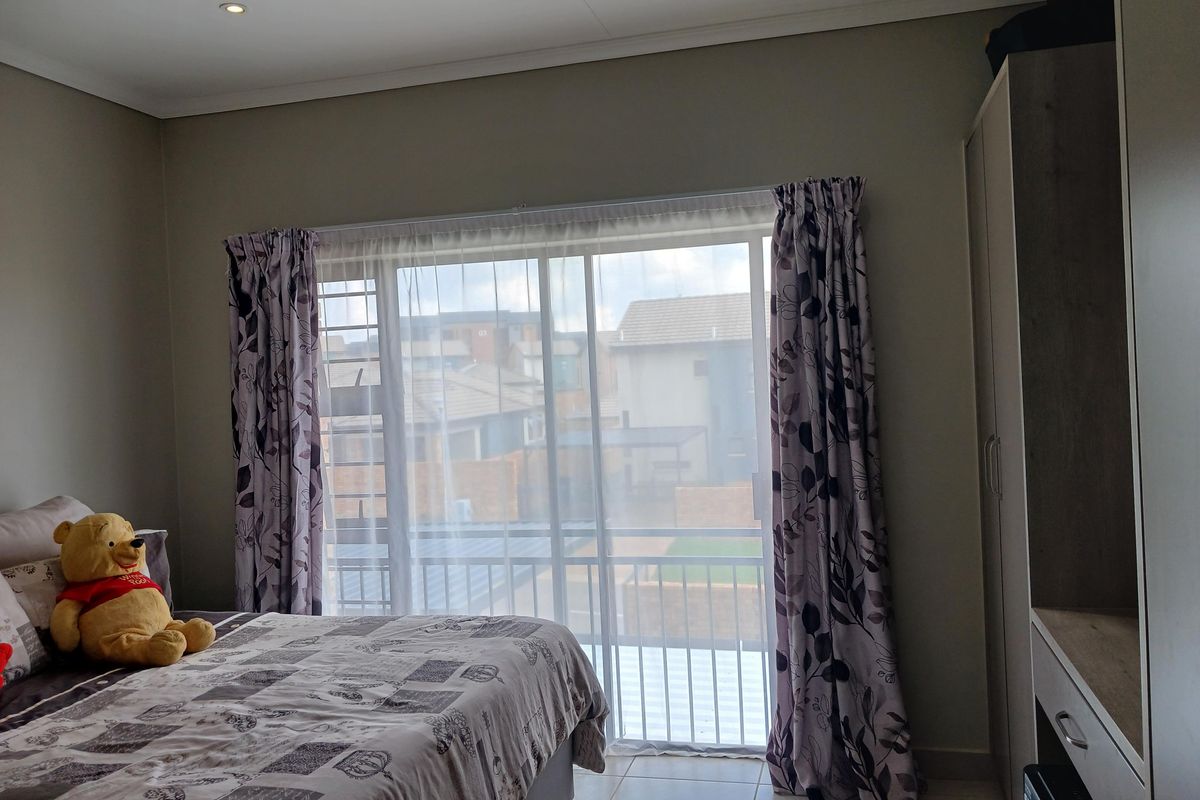 A well-lit bedroom featuring tiled flooring, built-in cabinetry, and a sliding glass door that opens to an exterior balcony.