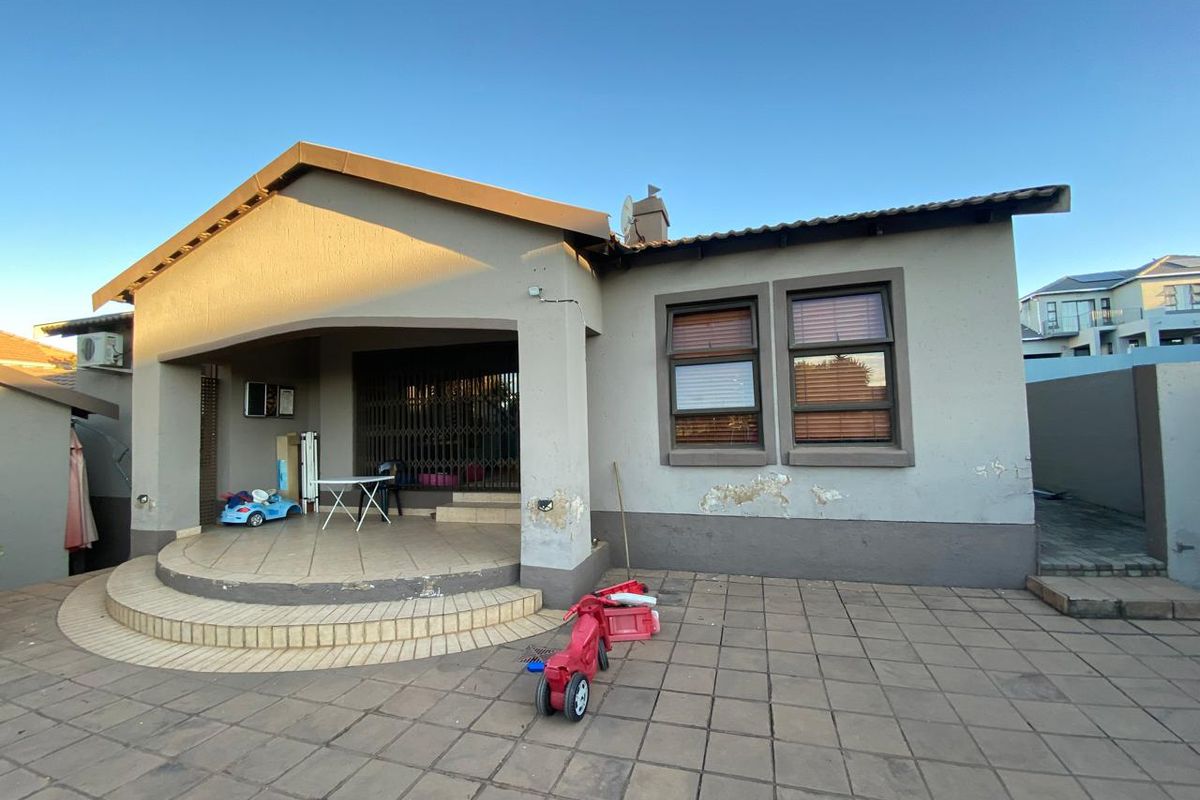 Rear view of the house featuring a covered patio area, tiled flooring, and exterior wall finishes showing signs of wear.