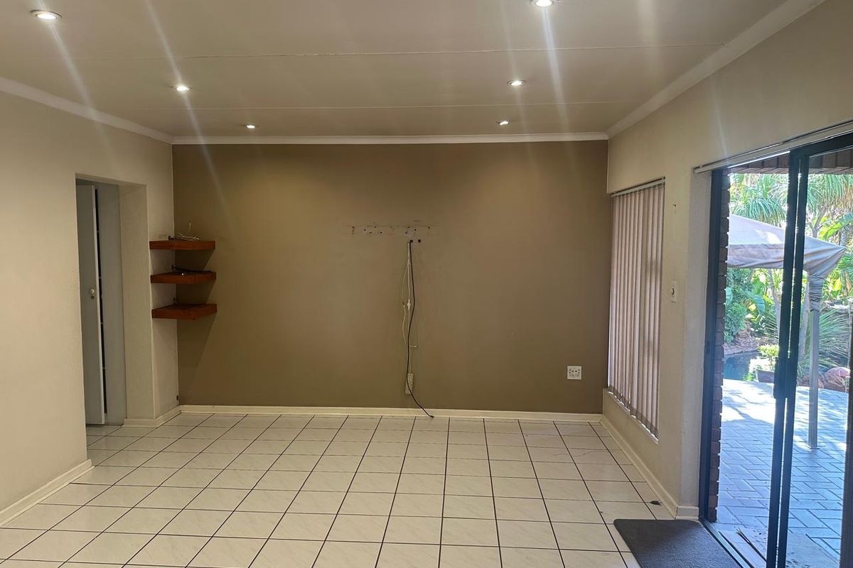An empty living room featuring tiled flooring, recessed ceiling lighting, and sliding glass doors providing direct access to the outdoor patio area.
